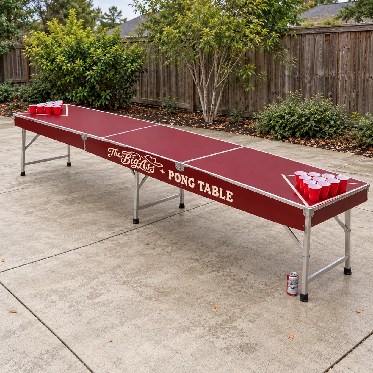 Oversized red Big Ass Pong Table with folding metal legs in a backyard setting.